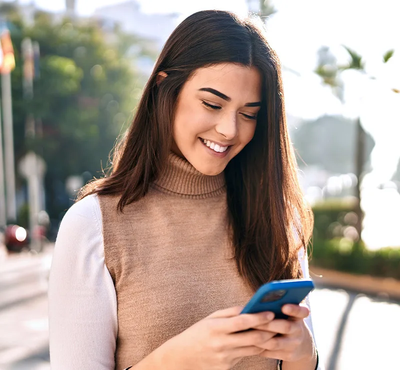 Eine Frau, die lächelnd auf ihr Smartphone schaut
