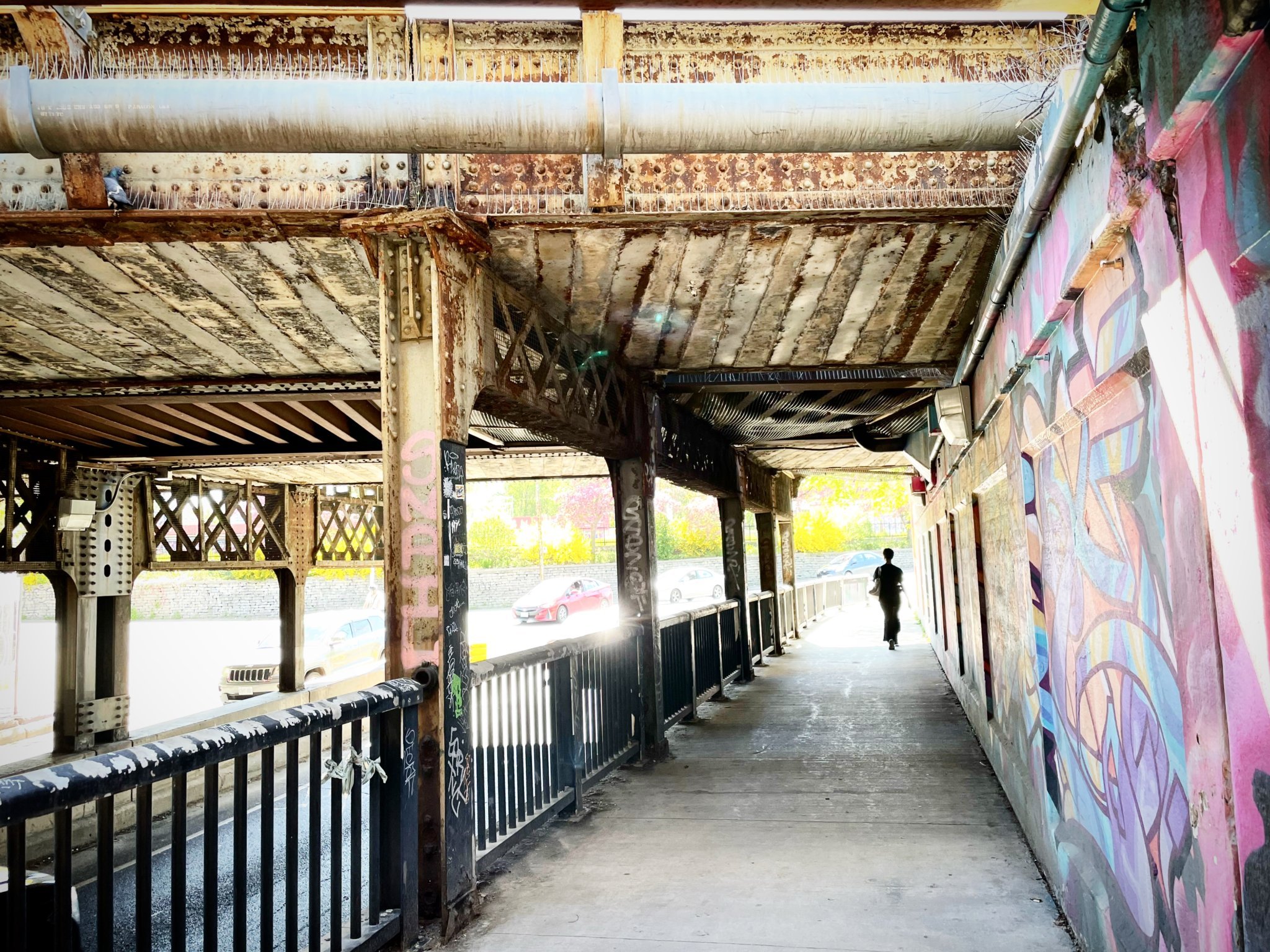Person walking under rail bridge