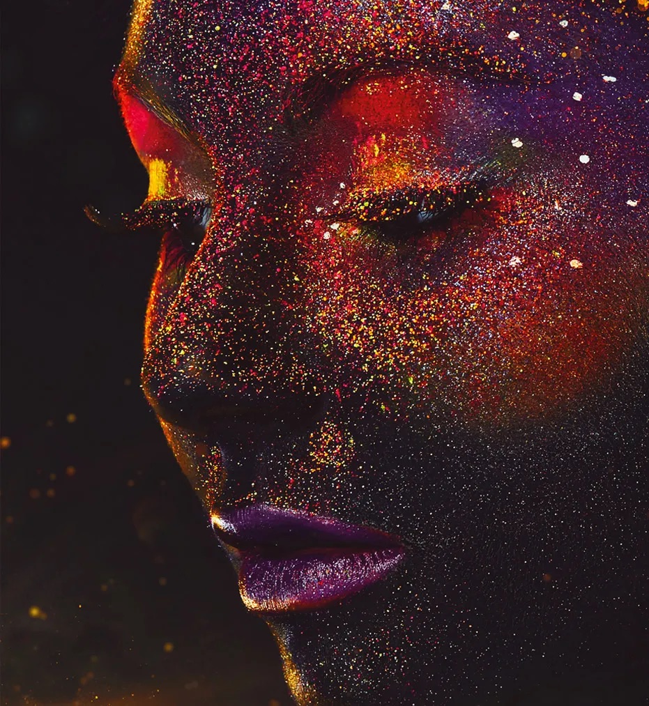 An abstract picture with a face of a woman with sparkling glitter on her face, in red, purple and black.