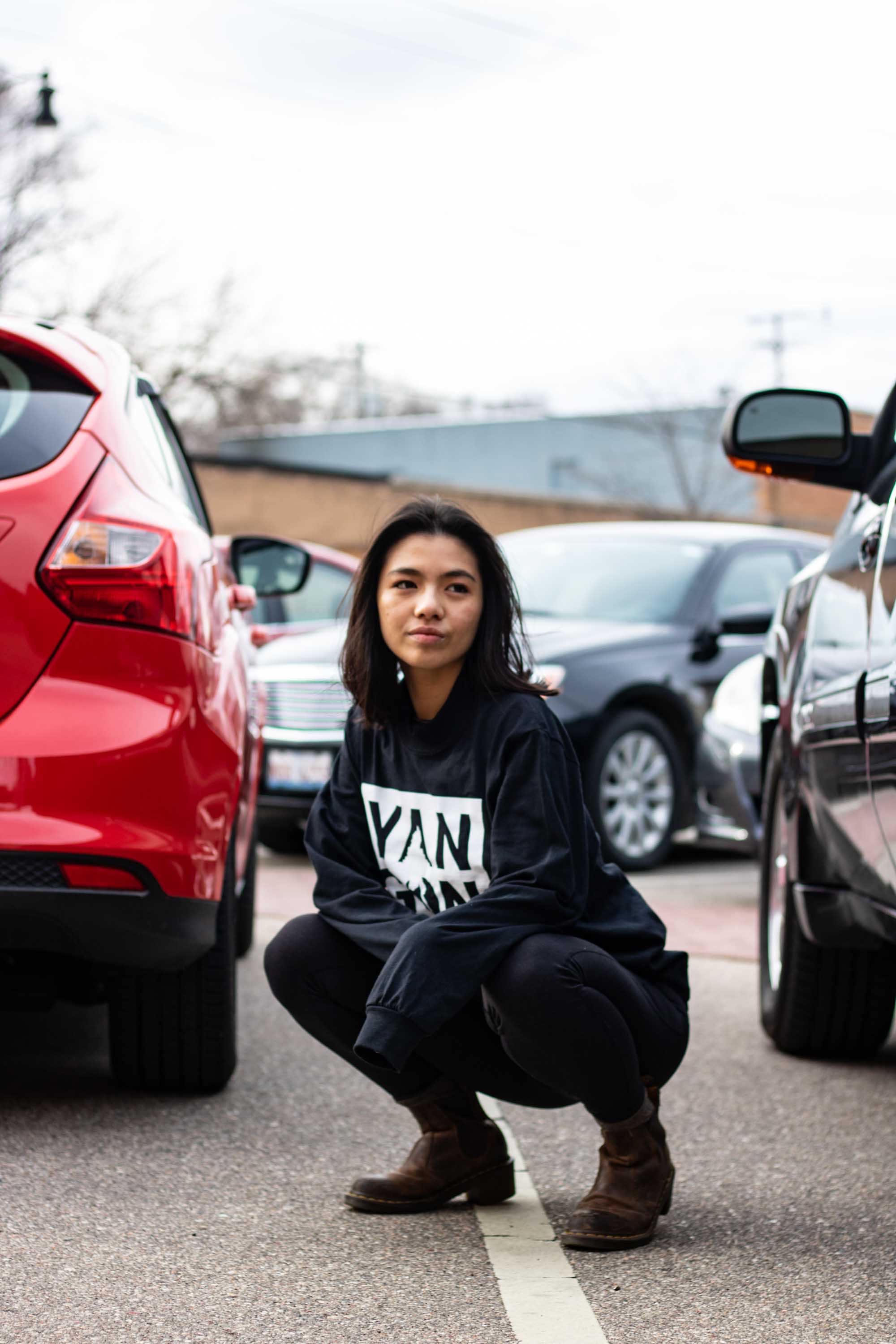 Person squatting in between cars in parking lot