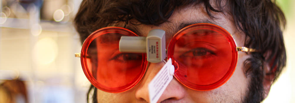 Person wearing large round red glasses with shopping tags on
