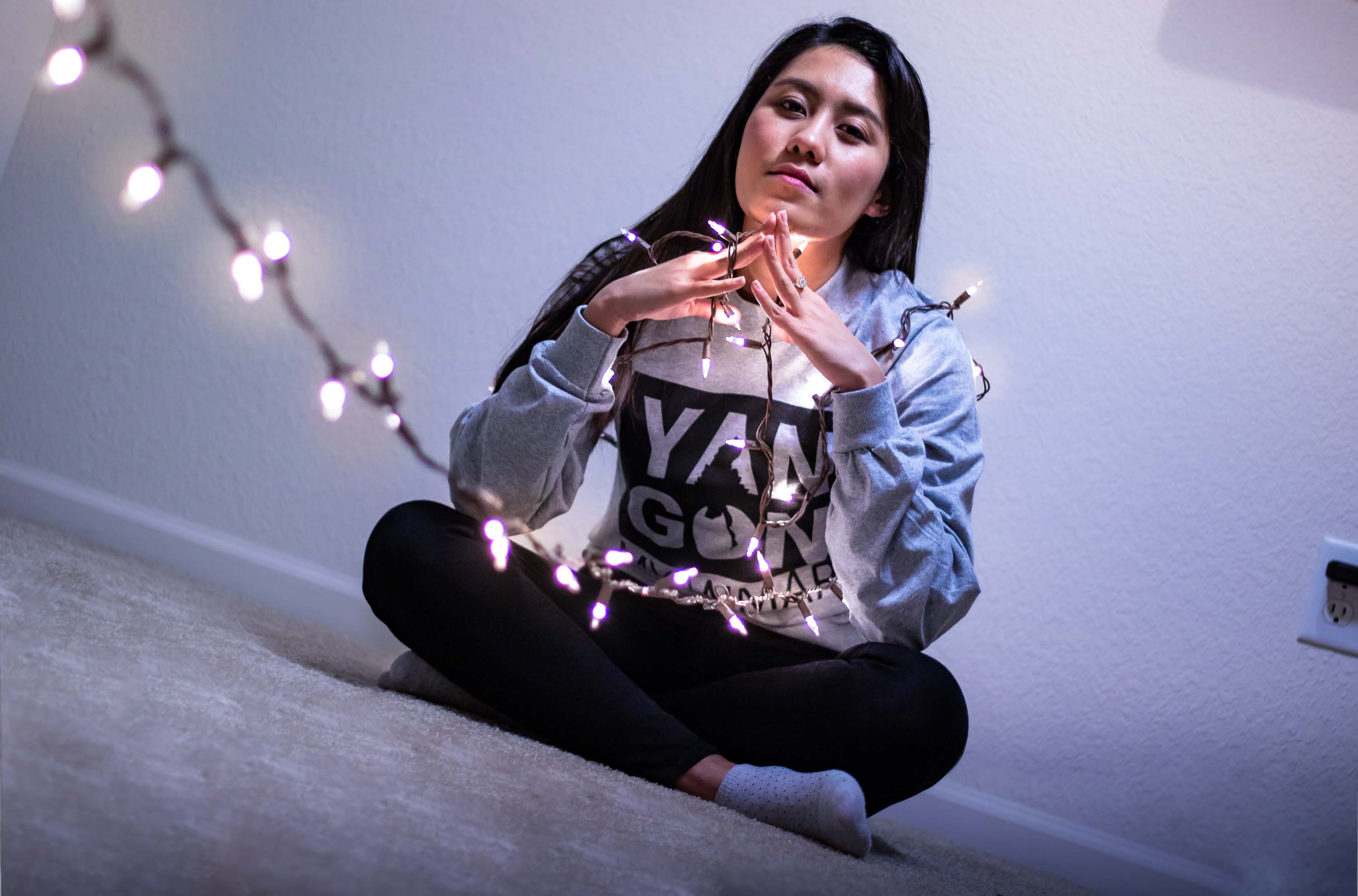 Person sitting cross legged while wrapped in string light