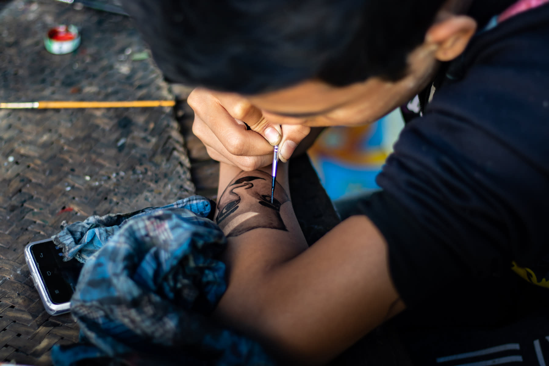 A person drawing a face on their own arm using a brush