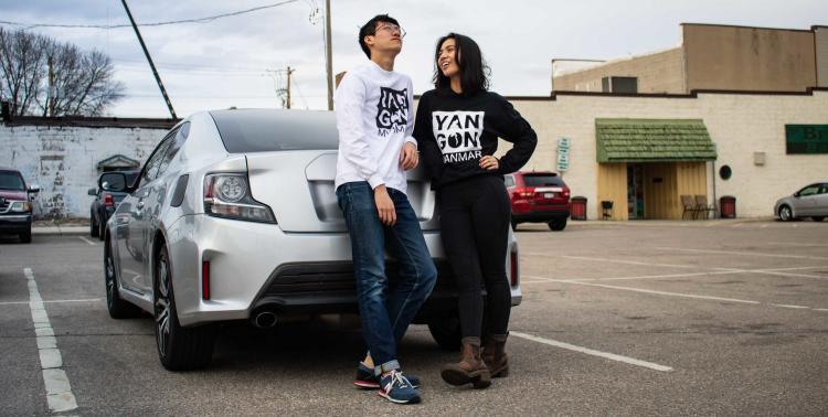 Two people chatting while leaning on car