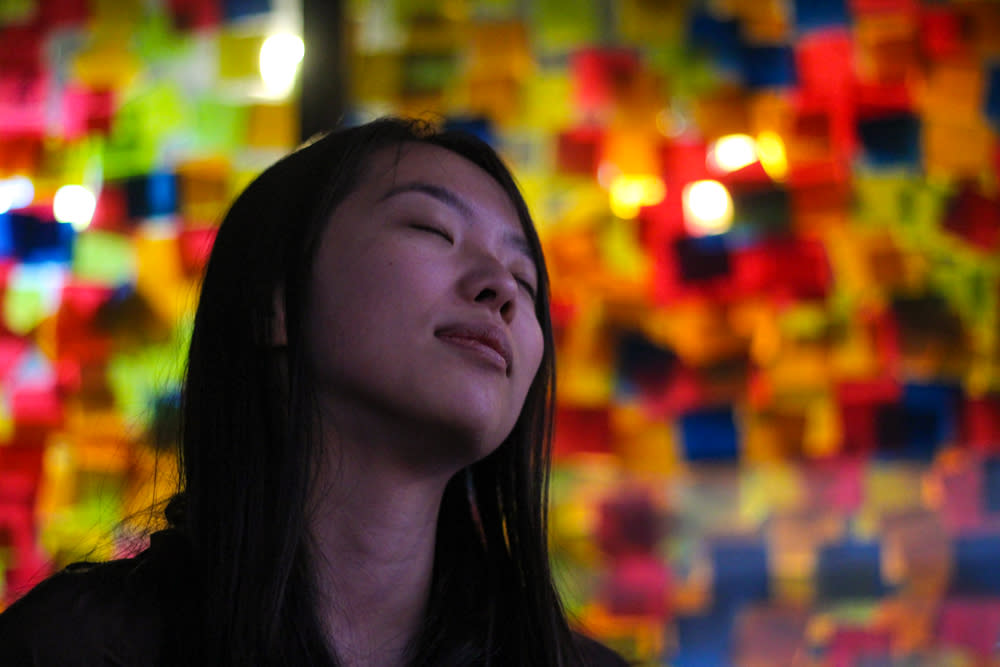 Person with closed eyes in front of a wall of sticky notes