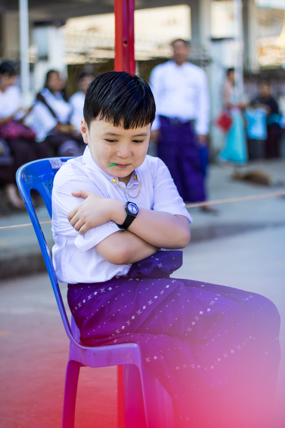 A child sitting on a blue chair with arms crossed