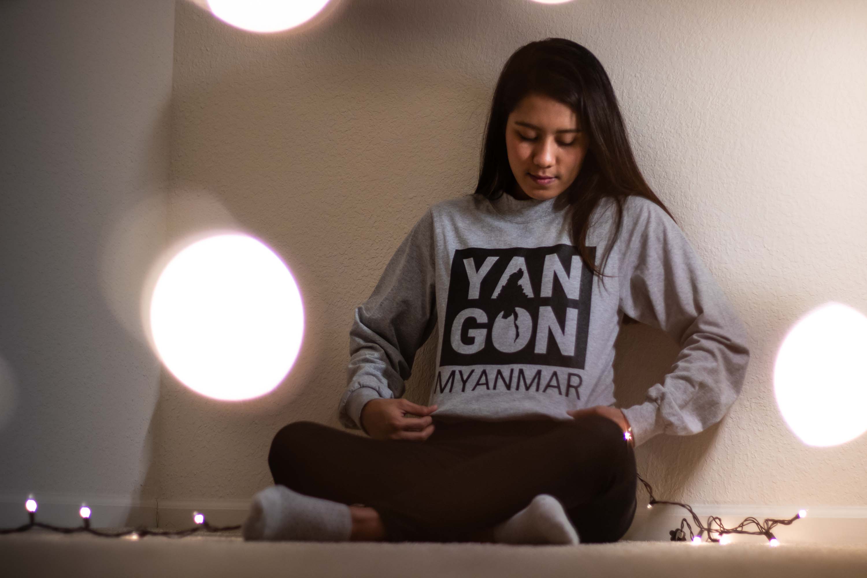 Person leaning on wall, looking down at her sweater