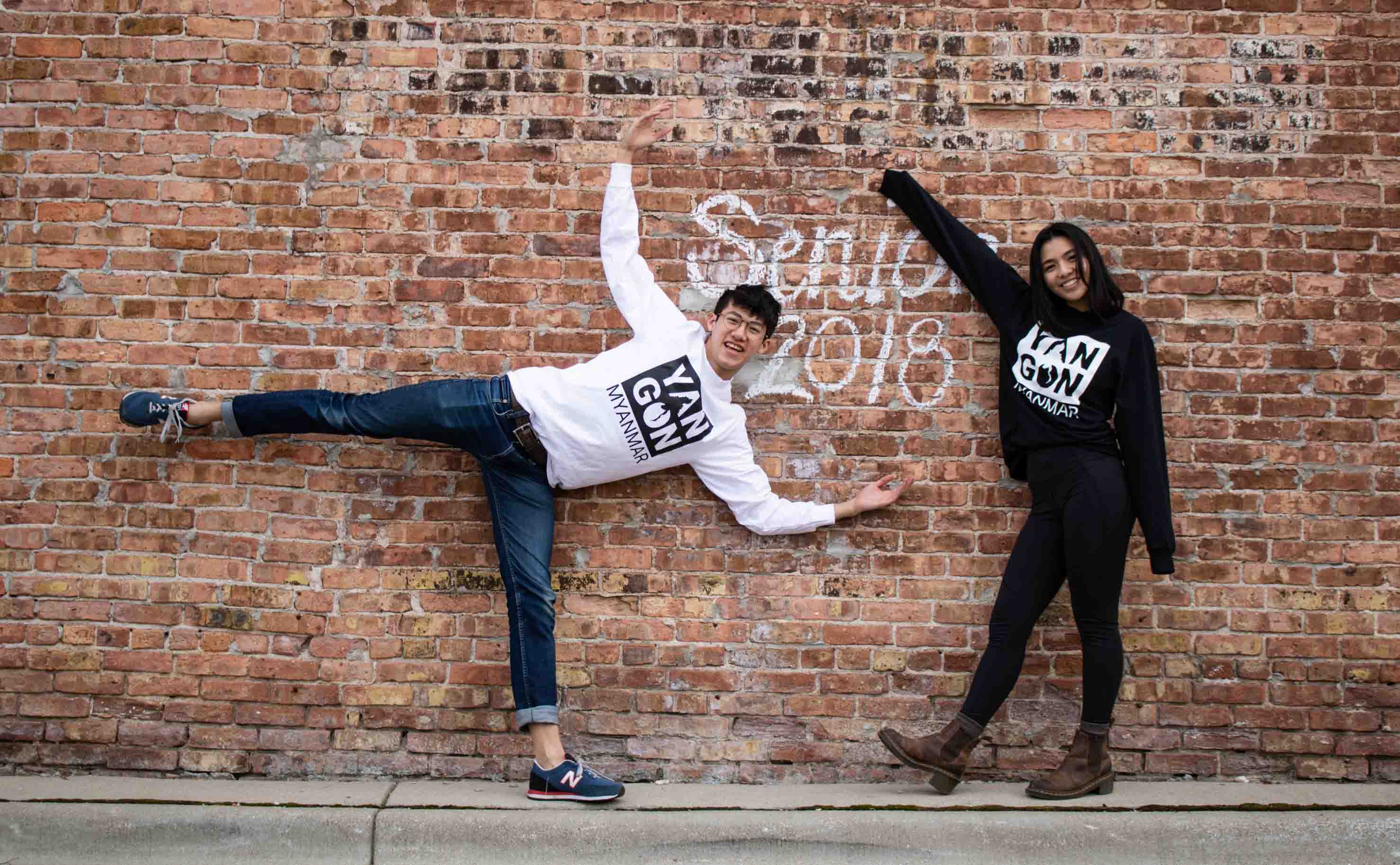 Two people posing in front of a brick wall