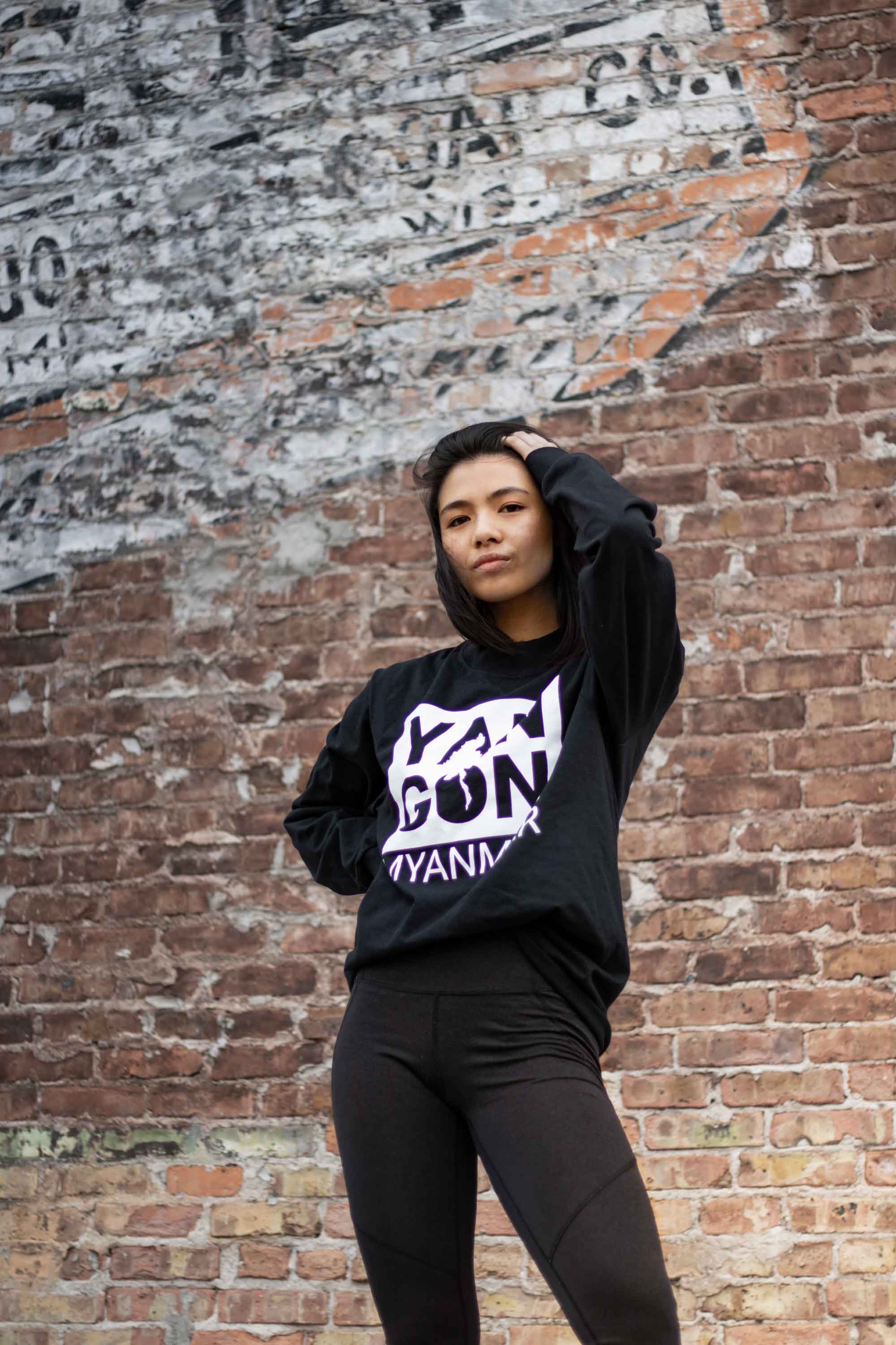 Person posing for camera in front of brick wall