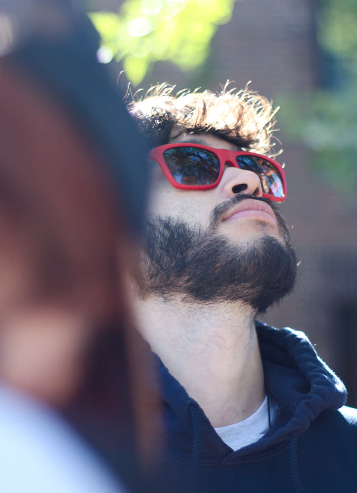 Personal in red-brimmed sunglasses looking up