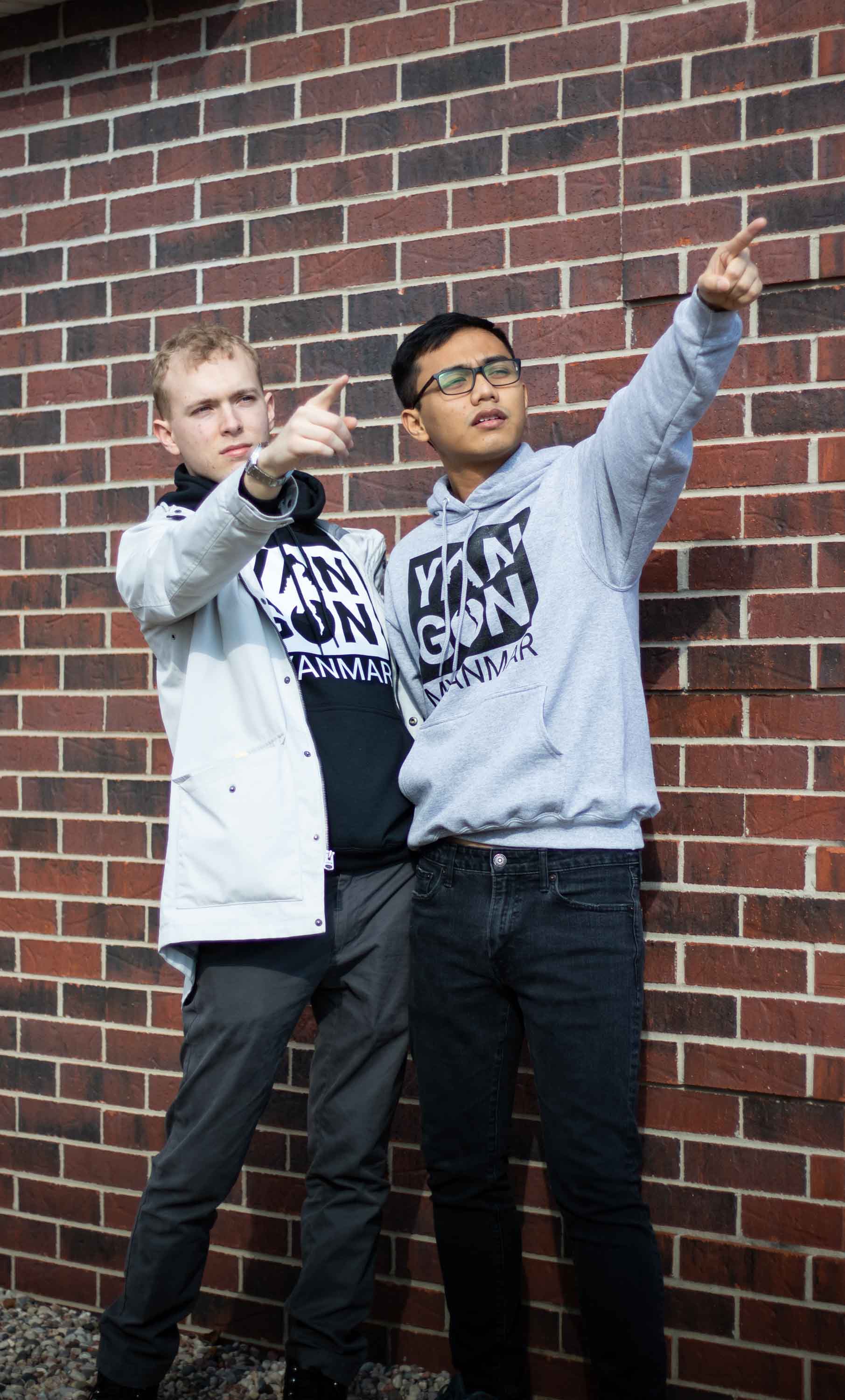 Two men pointing right in front of the bricks