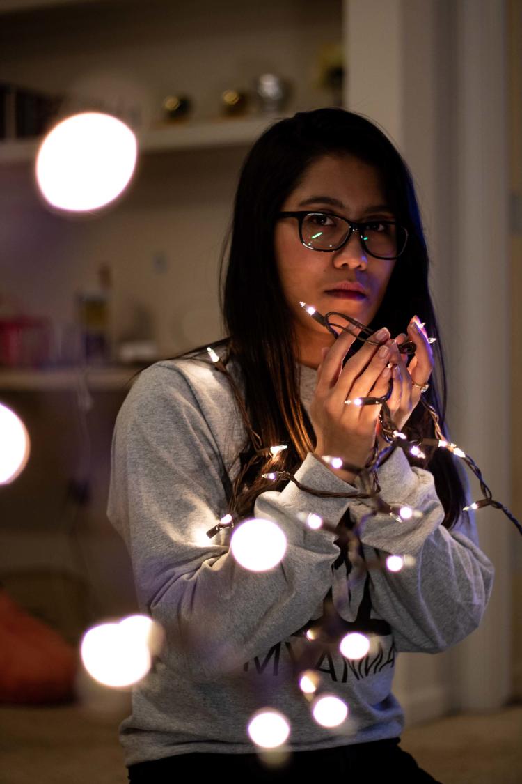 Person looking at camera while holding string lights