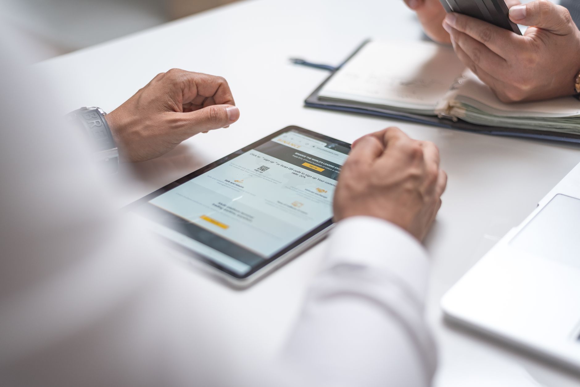 Fachleute prüfen gemeinsam ein Tablet und ein Smartphone während eines Gesprächs · Foto: AlphaTradeZone (Pexels)