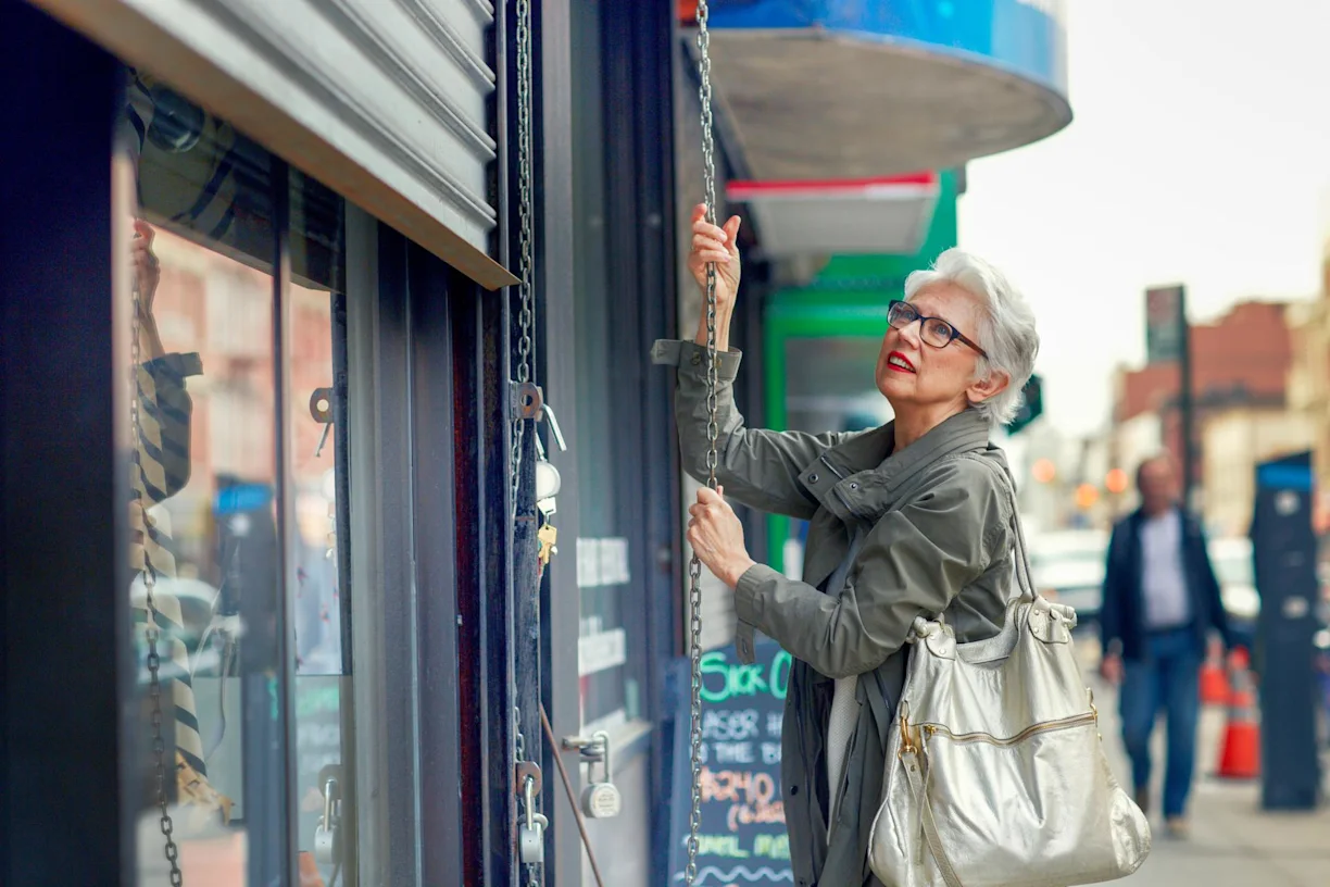 A woman closing the shutters on a shop front