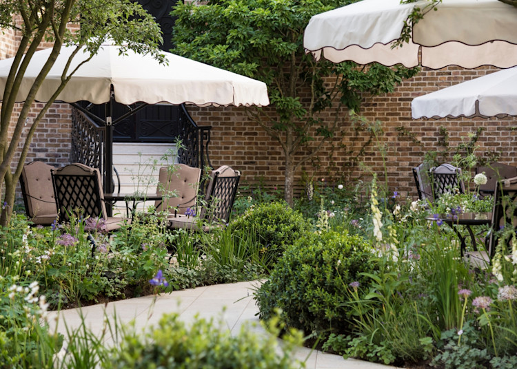 Outdoor dining garden patio with tables, chairs, umbrellas, and flowering plants