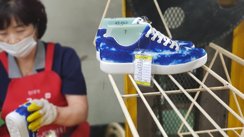 A factory worker checks the Atoms Tie-Dye Blue sneakers.