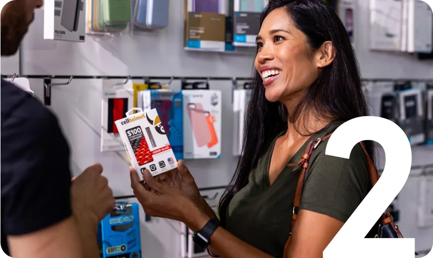 Customer smiling while holding a screen protector package in a phone accessory store, representing mobile device protection and repair add-ons.