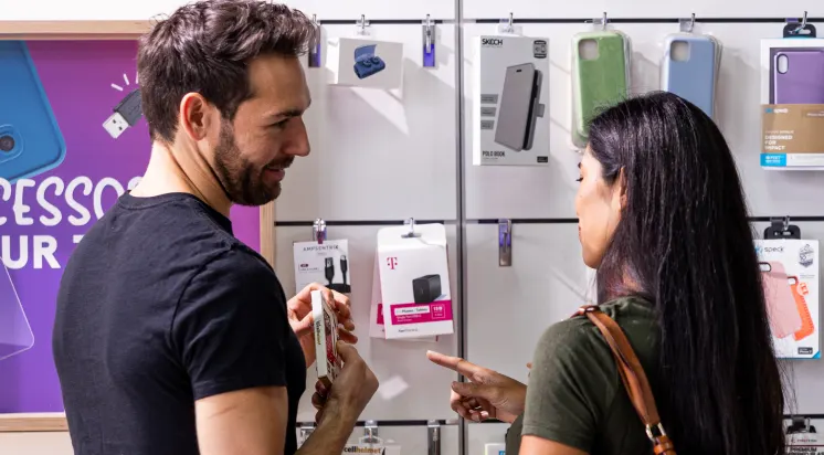 Customer receiving assistance while browsing phone cases, screen protectors, and mobile accessories in a retail electronics store.