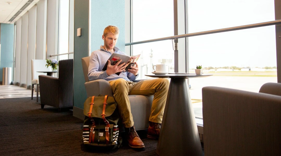 Homem desfrutando de uma leitura em uma sala de espera do aeroporto