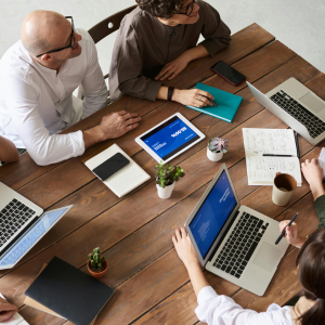 Group of people sitting around a table with laptops and talking