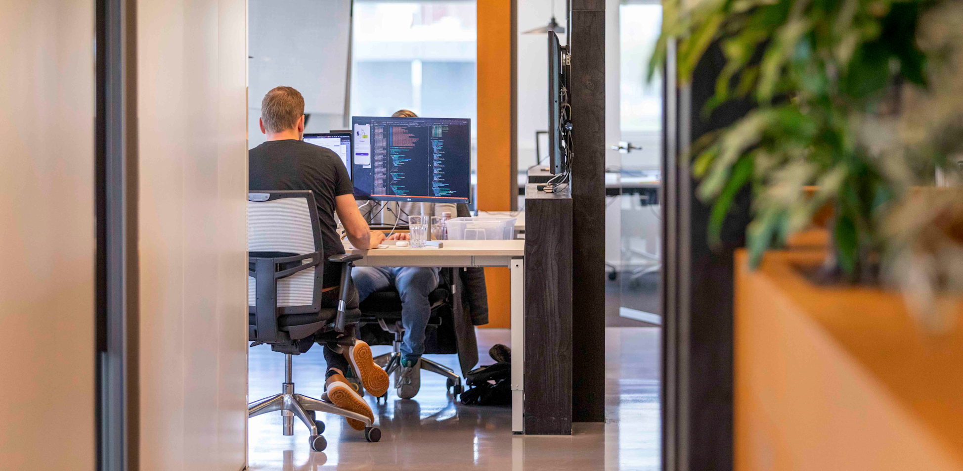 Je ziet in de verte een developer werken aan een werkeiland. 