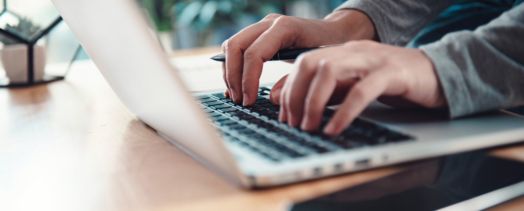 Een persoon typt op een laptop aan een bureau 