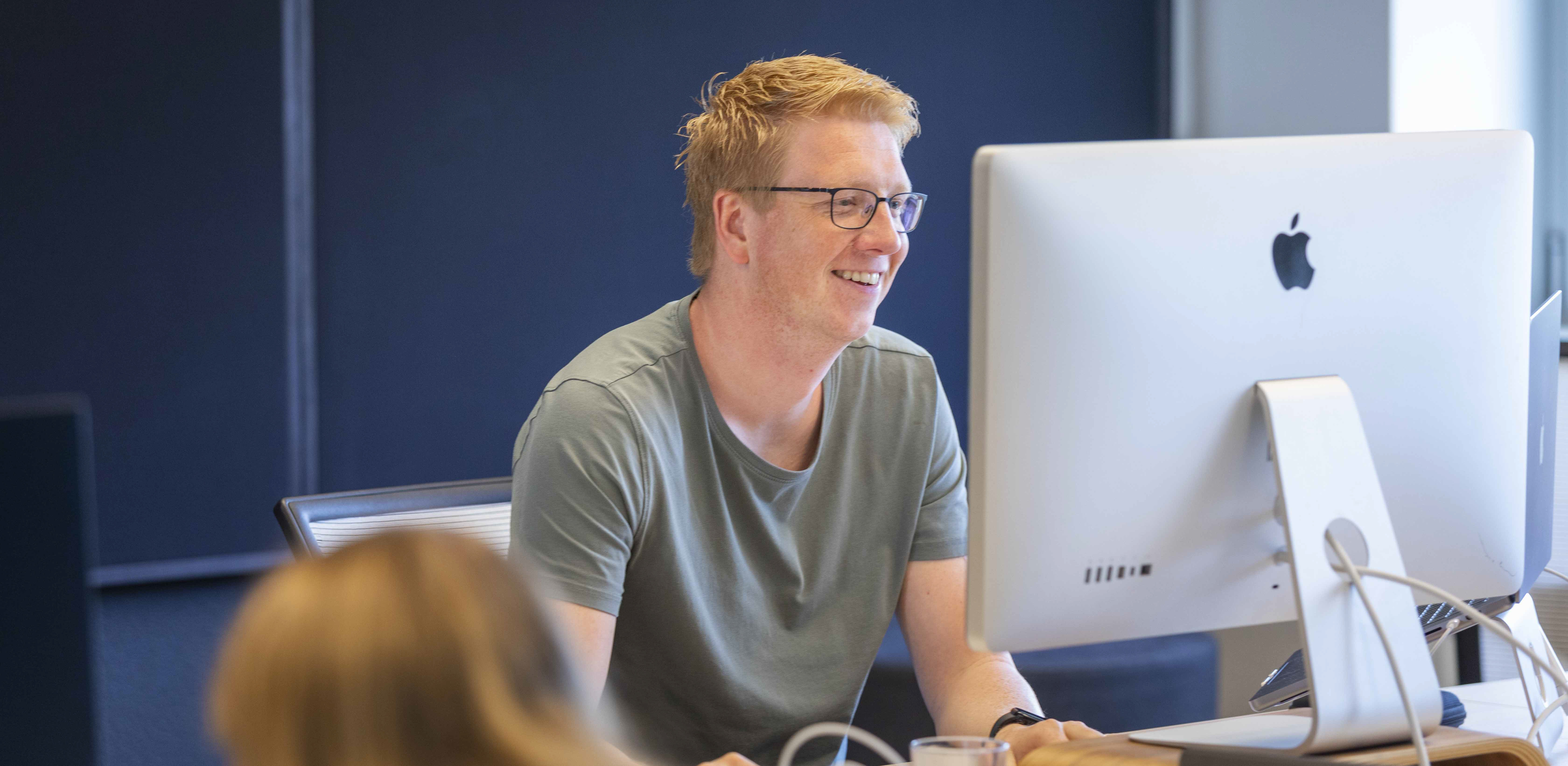 Stef, UX designer, werkt aan een iMac.
