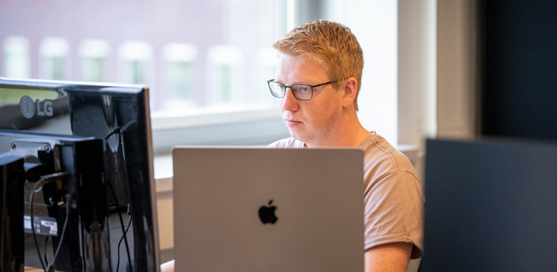 UX designer Stef is druk aan het werk naast het raam. 