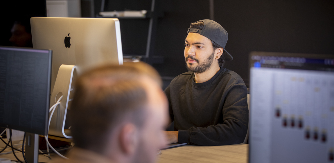 Een developer (Renzel) werkt aan een iMac samen met een designer (Boy). 