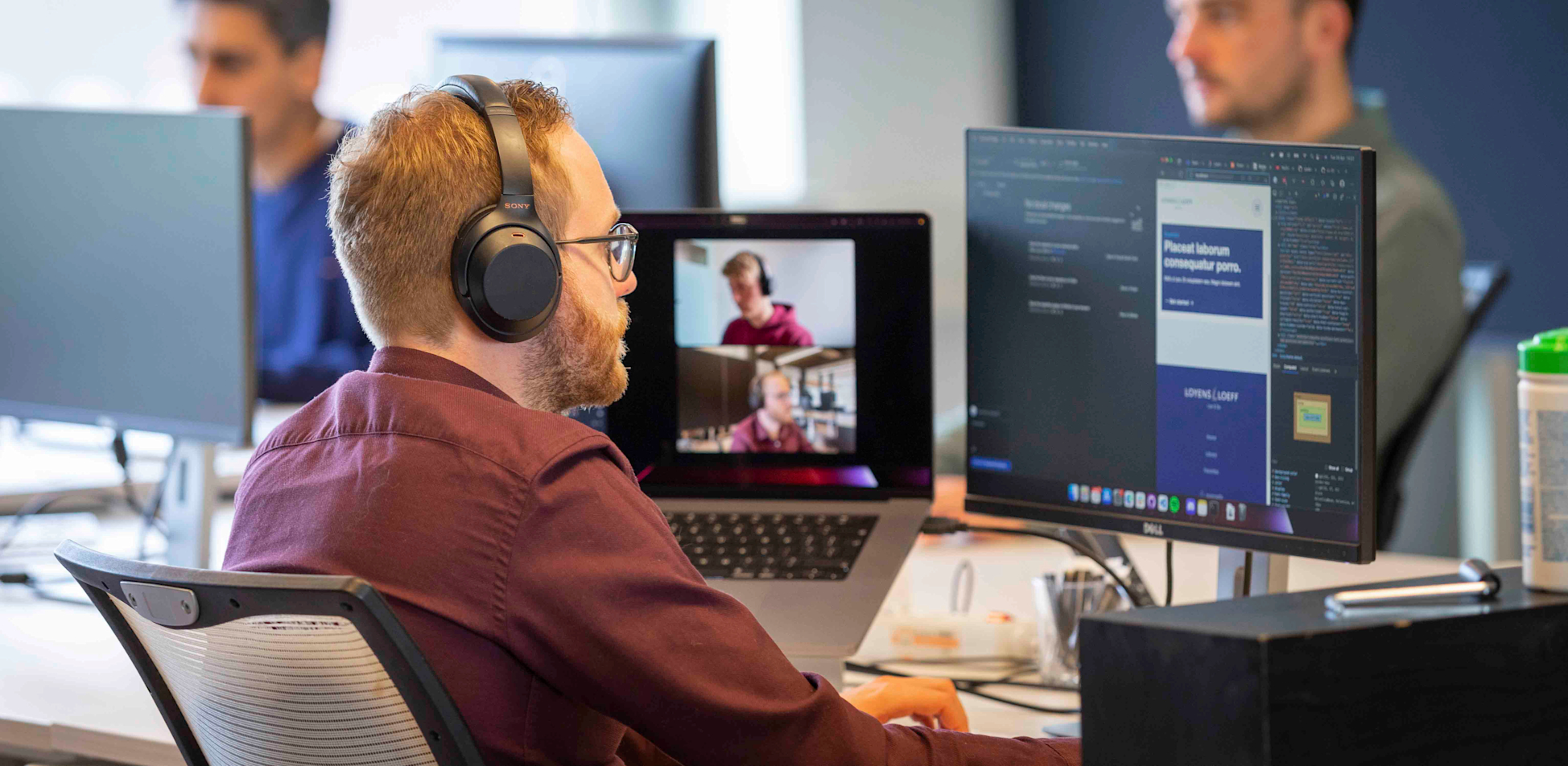 Een paar collega's werken samen aan een werkeiland, waarvan er 1 aan het bellen is met een thuiswerker.