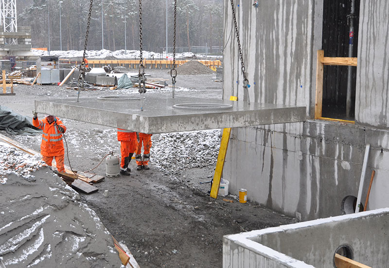 Die Abdeckplatte mit Aussparungen wird auf das bereits platzierte Betonelement hebt. 