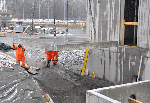 Die Abdeckplatte mit Aussparungen wird auf das bereits platzierte Betonelement hebt. 
