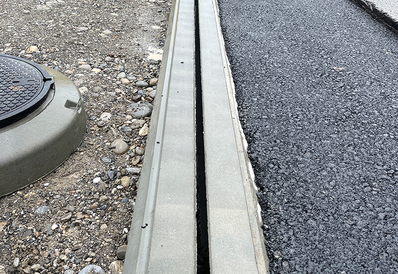 Caniveau à fente en béton récemment installé sur une autoroute pour assurer un drainage optimal de la chaussée