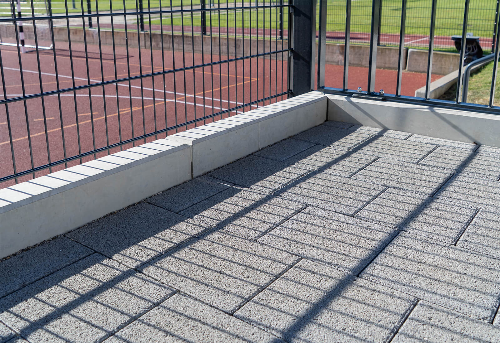 Sickersteine und Randsteine für eine Terrasse oberhalb eines Sportplatzes. 