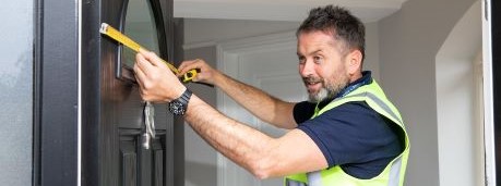 A man in a hi-vis measuring the door 