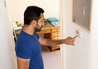 Smart Hints & Tips: Heating system tips IE HE A man checking the thermostat