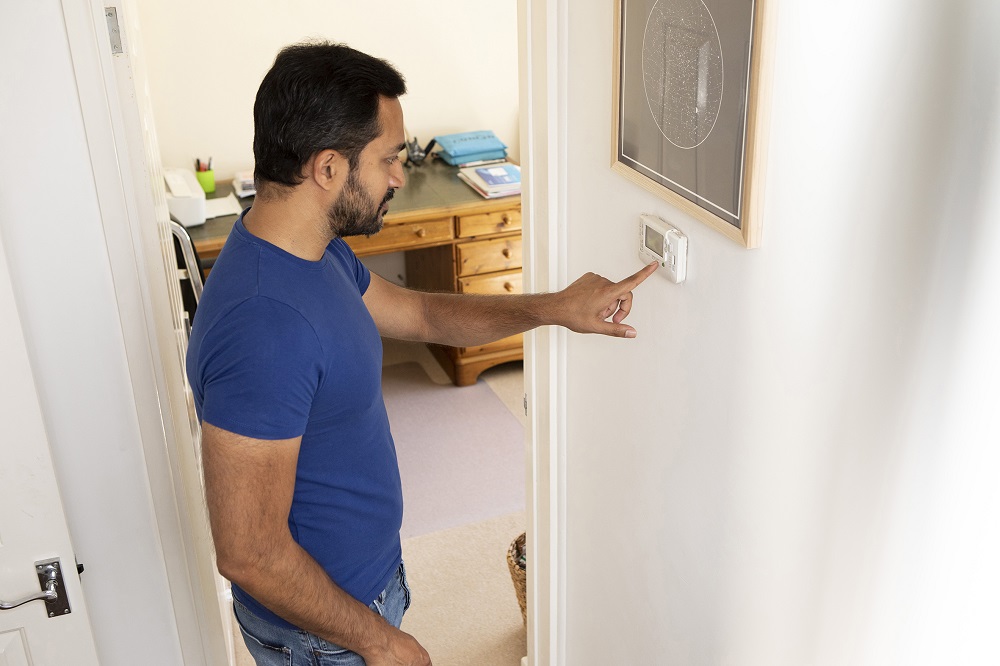A man checking the thermostat