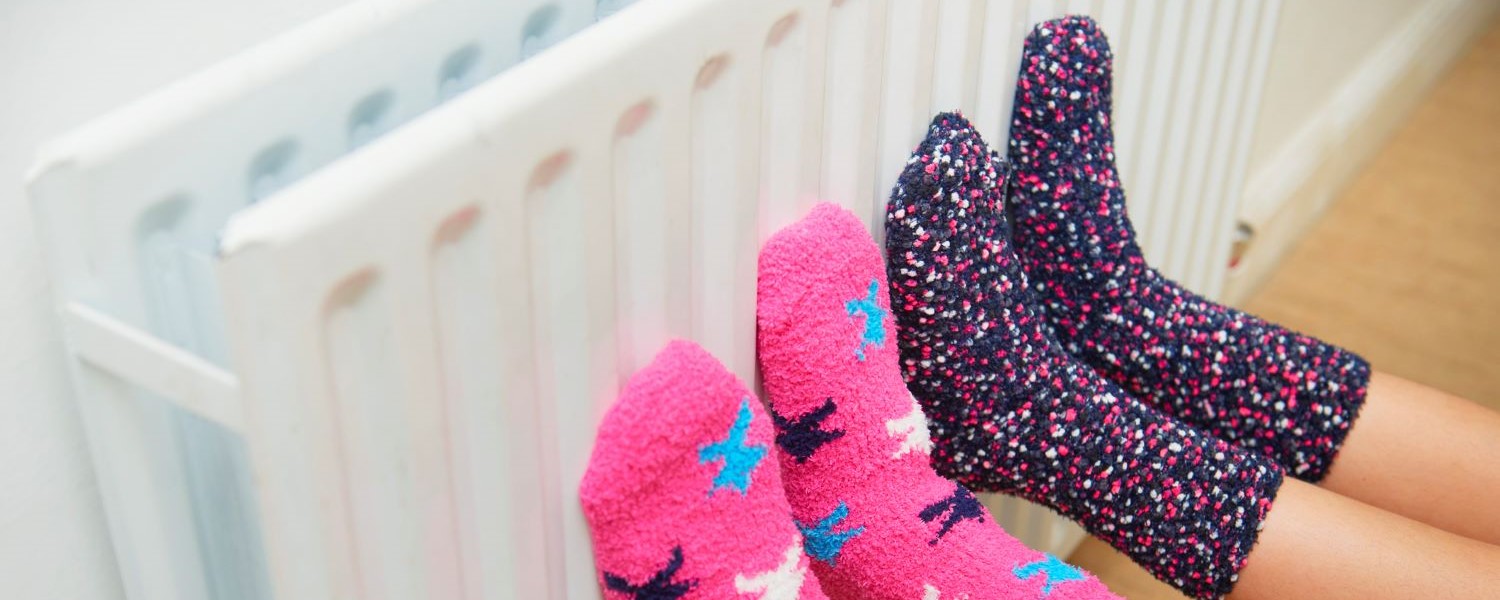 Warm cosy heater.jpg (full size) Two sets of children's feet wearing socks, resting on a heater