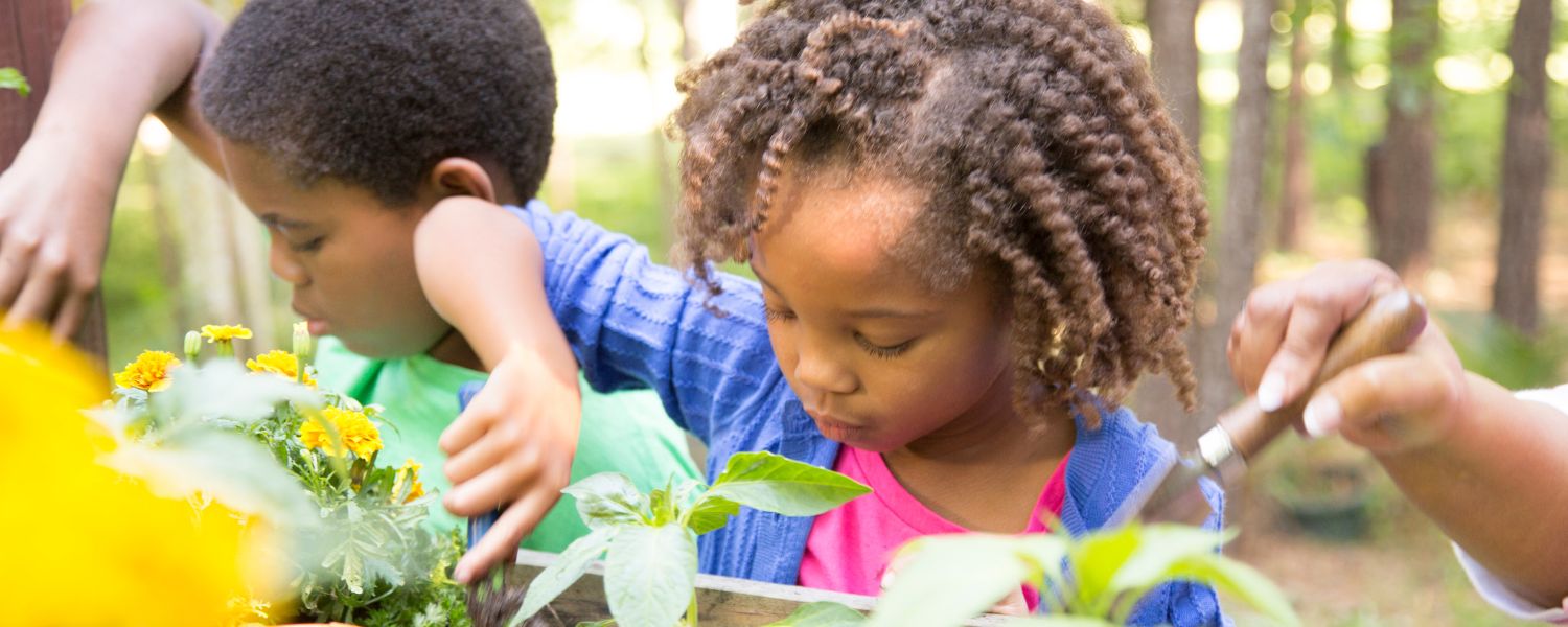 Two children tending to plants on an outdoor setting