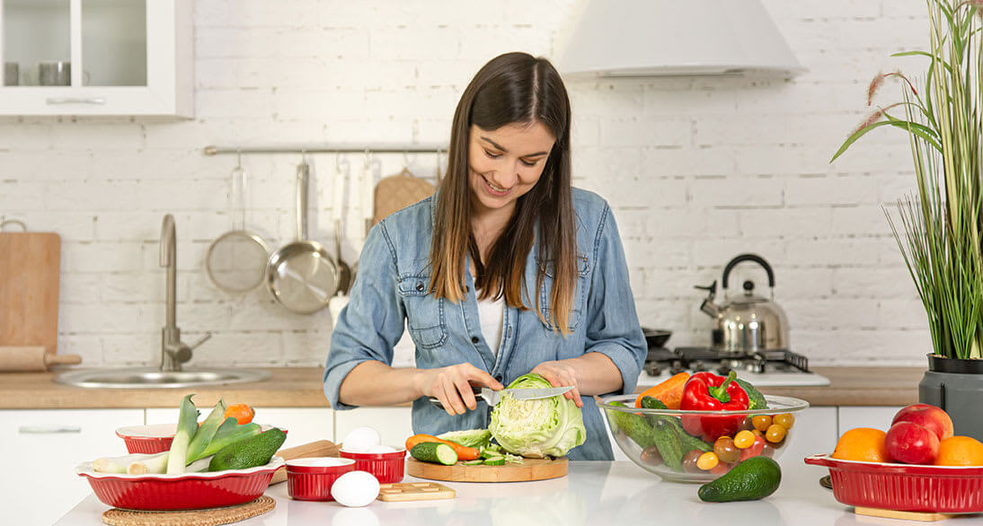 Mujer cortando vegetales en su cocina