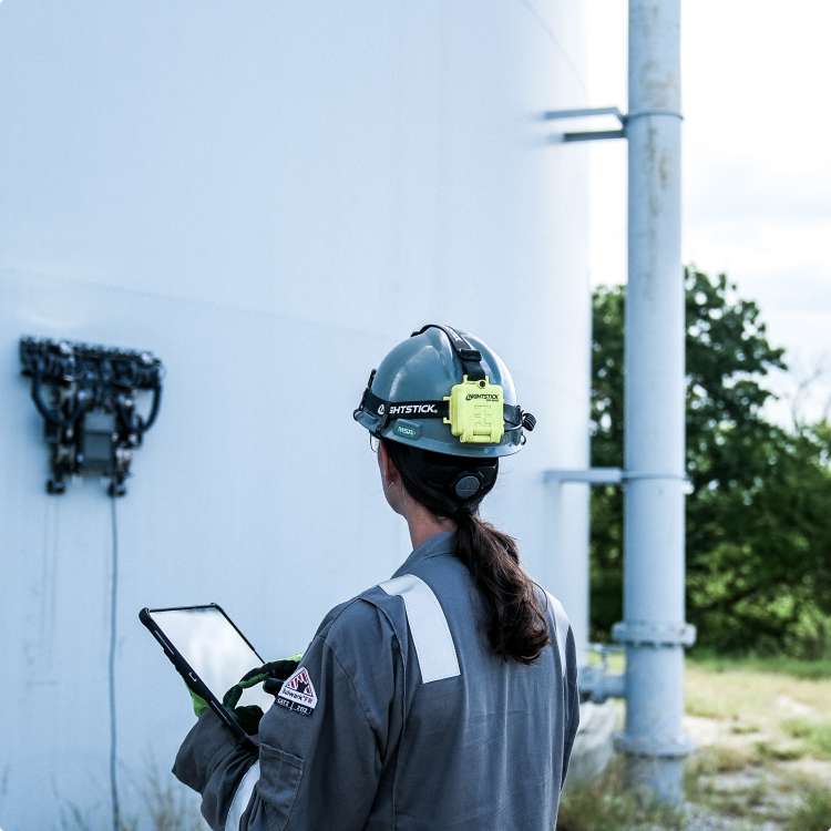 photo of a worker inspecting a robot working on the side of an industrial tank