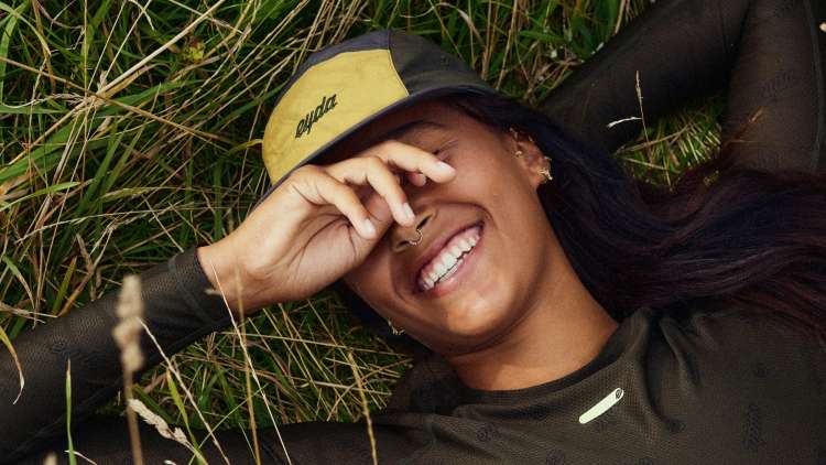 Image of woman wearing an EYDA hat while laying in tall grass