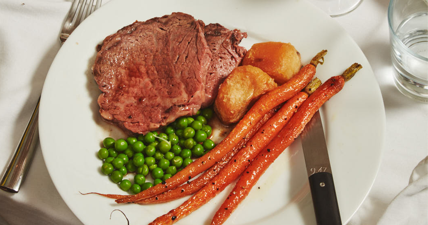 Bone-In Ribeye Roast With Roasted Carrots, Crispy Potatoes, Peas And Yorkshire Puddings
