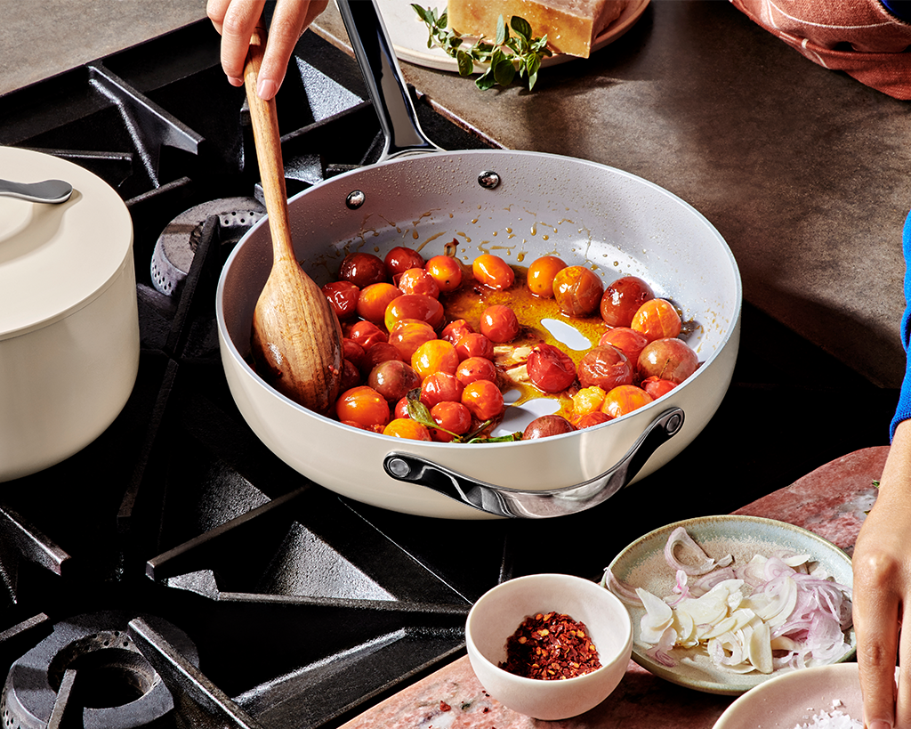 Cooking tomatoes with a wooden spatula in a saute pan