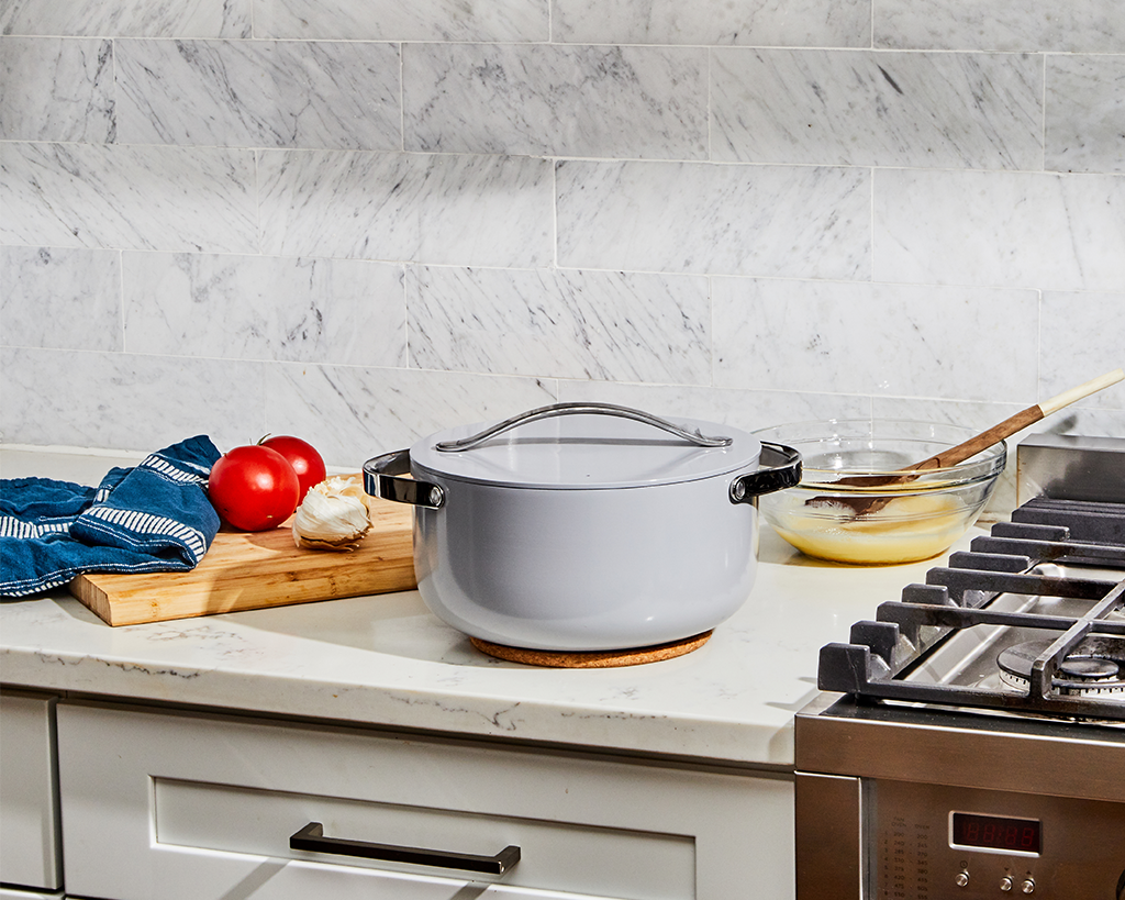 A ceramic white dutch oven sitting on a pot holder