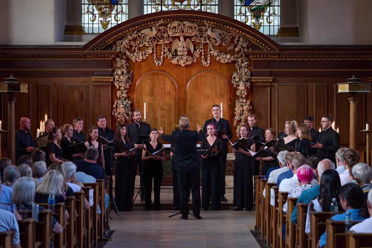 the tenebrae choir sings in an ornate church with audience members visible wearing all black