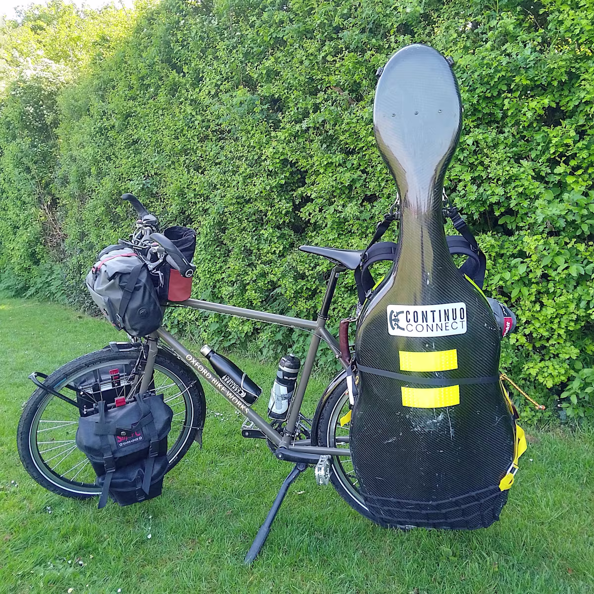 Pedalling for the Planet: Sarah Small completes epic ‘Good Again?’ cycling tour a touring bicycle loaded with a large instrument case in a garden