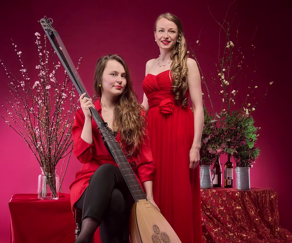 Sweeter Than Roses soprano angela hicks and lutenist kristiina watt wearing red dresses with a festive background