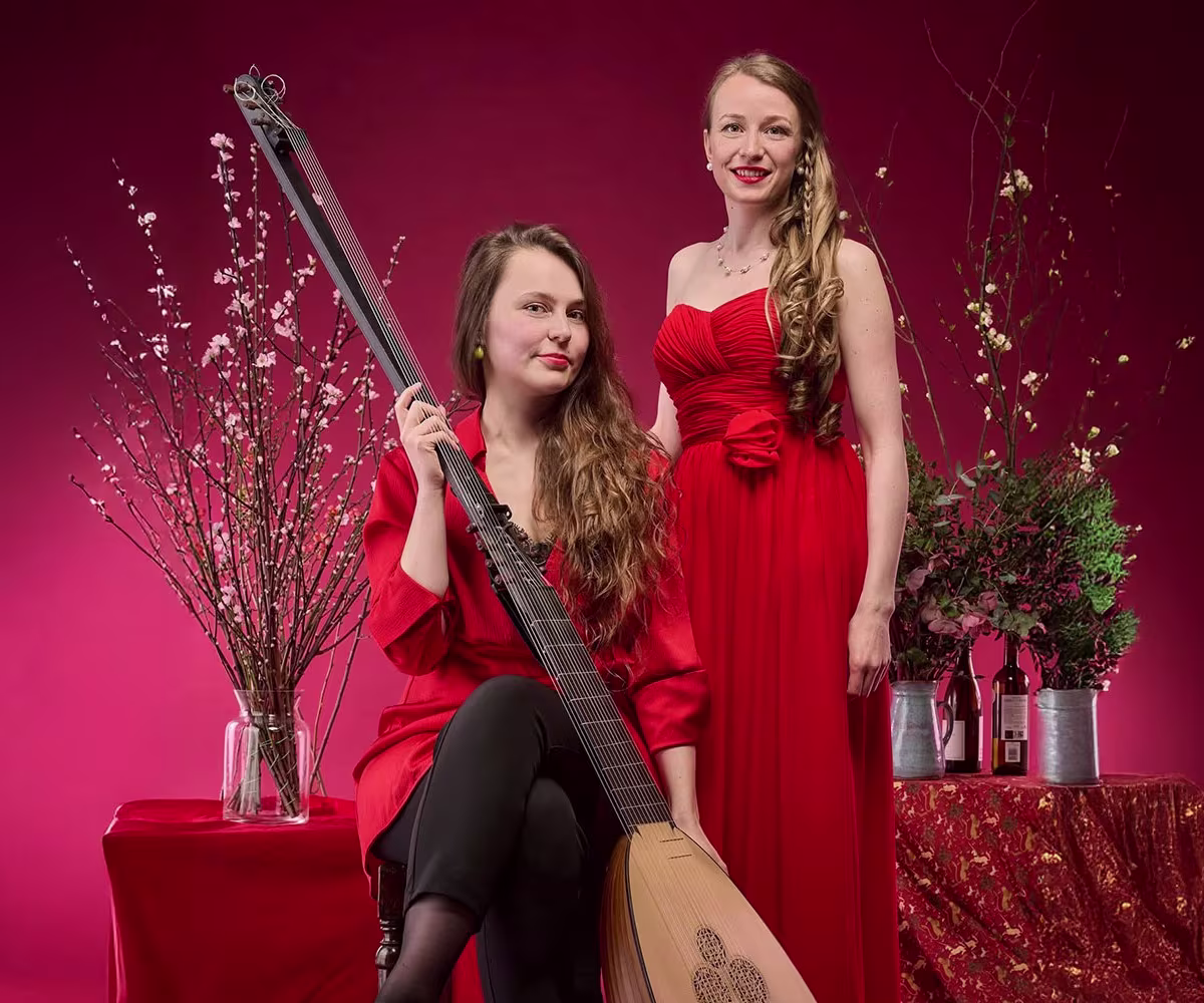 Sweeter Than Roses soprano angela hicks and lutenist kristiina watt wearing red dresses with a festive background