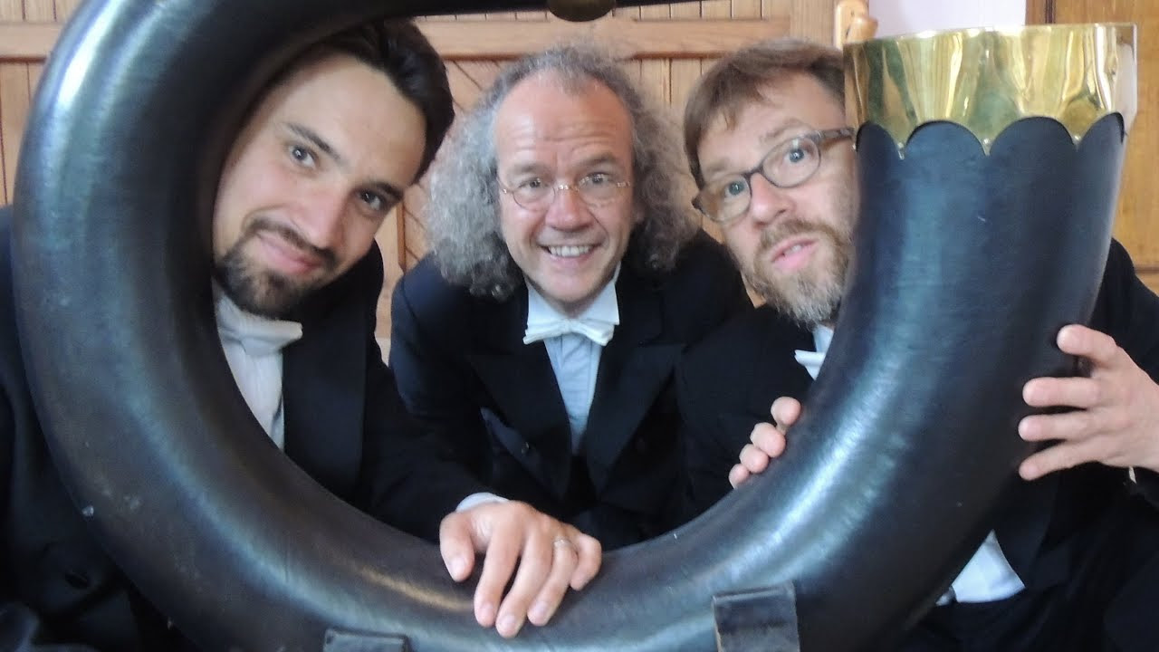 three men in tuxedos and the bell of a serpent instrument
